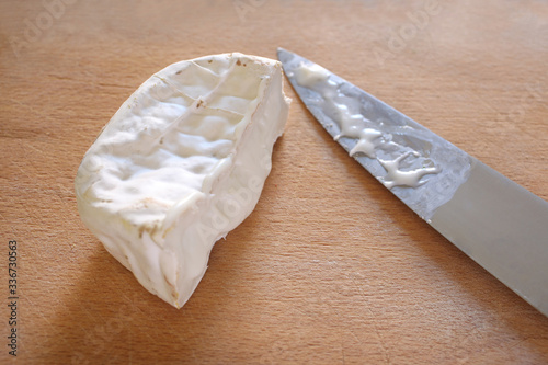 cut goat cheese and knife blade rest on a wooden table with copy space for your text