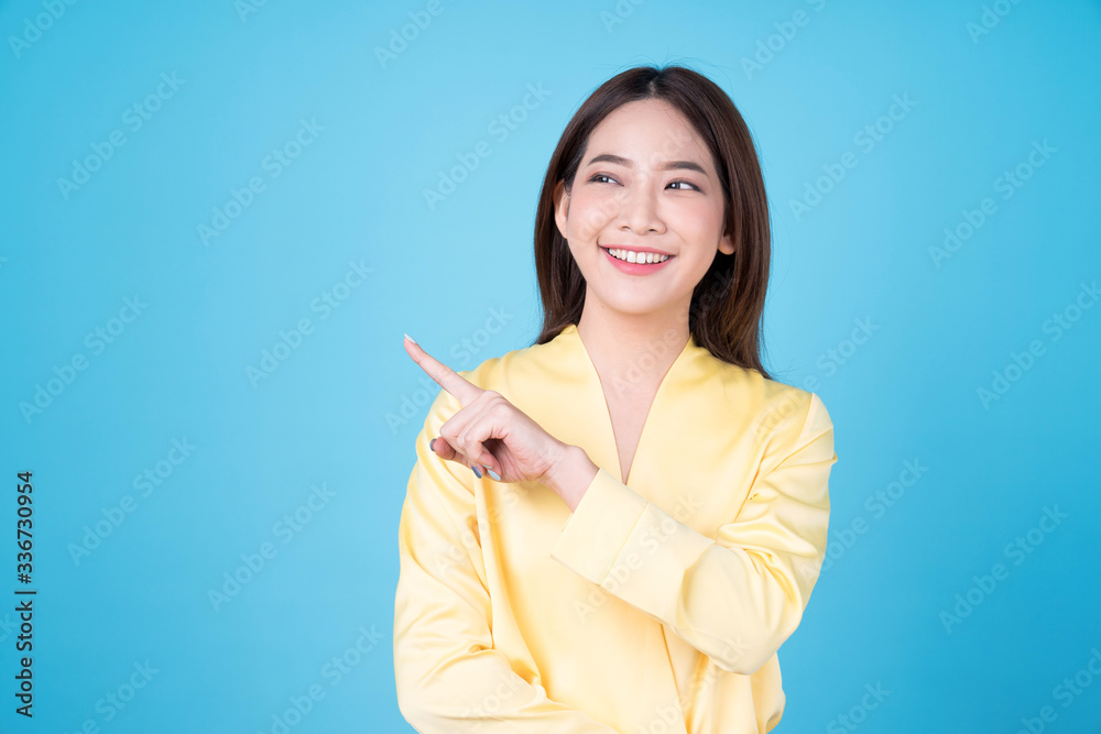 Young beautiful asian woman pointing to copy space, isolated on blue background. Young beautiful asian woman pointing to copy space, isolated on blue background.