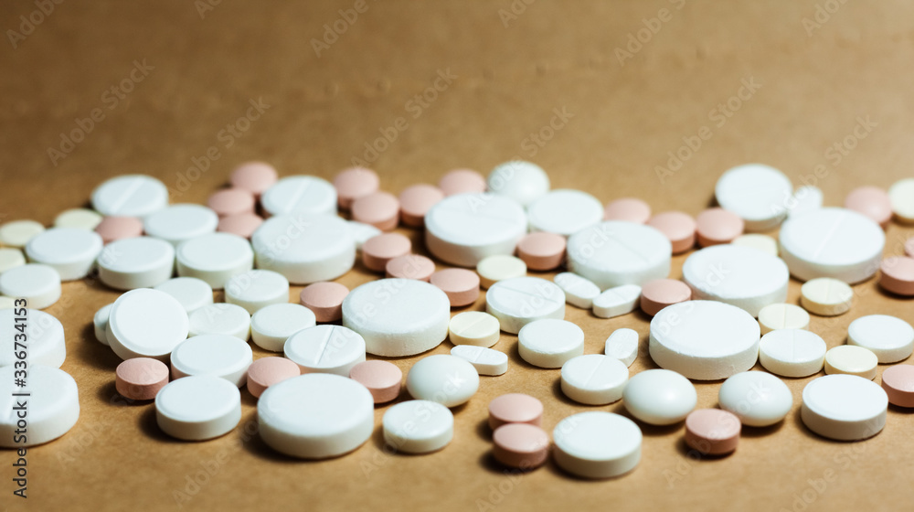 Heap of white pills, tablets, capsules on yellow orange background. Drug prescription for treatment medication health care concept wth copy space. Heap of white pills, tablets, capsules on yellow orange background. Drug prescription for treatment medication health care concept wth copy space.