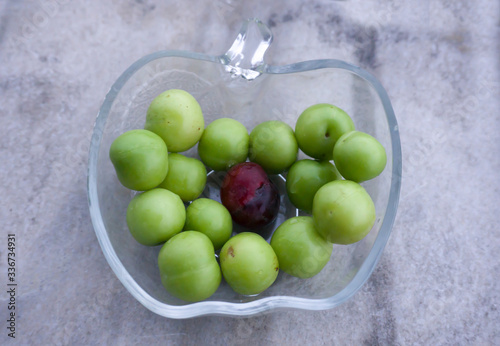 Heap of green sourish plums in glass bowl pot on white background. Fresh, organic and clean eating, healthy lifestyle conceptual photo. Agricultural background concept. To be different from others. 