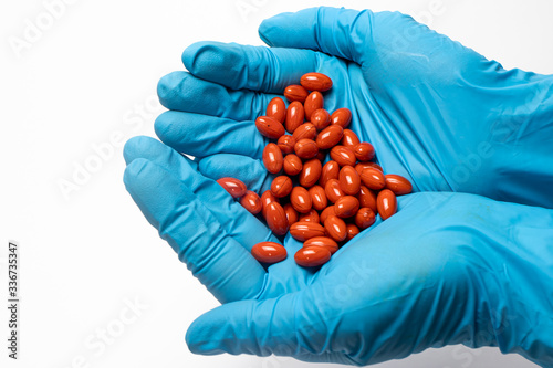 A handful of red lutein tablets in the hands of a man. The benefits of lutein.