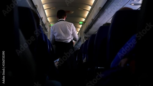 On board the flight are people on the plane and escorts in the aisle. Board the aircraft and the distribution of food. Cabin crew rear view