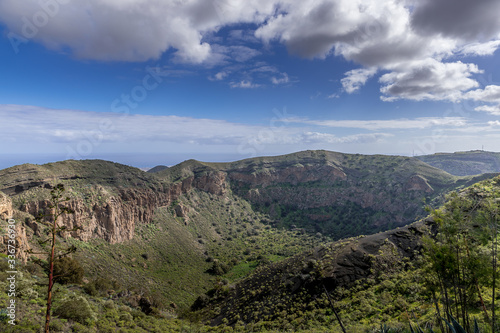 View of the mountainous landscape of volcanic origin along with lots of trees and vegetation and on the horizon, you can see the setting moon Gran Canary island