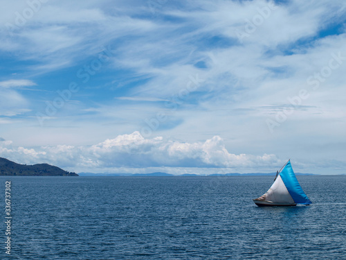 View of lake Titicaca with sailboat and clouds, Peru