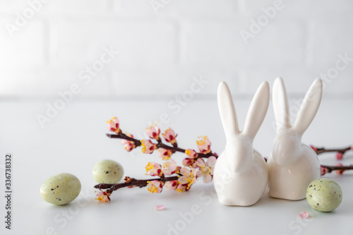 Easter spring decorative composition  with white easter ceramic bunny,  pink cherry branch. On a white background with place for text.