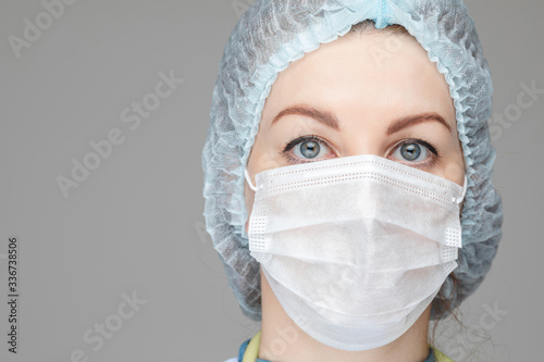Stock photo headshot of a female doctor or nurse in facial mask and hat protecting her from viruses. Covid-19 fighting. Real heroes of our time. photo