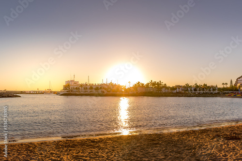 Sunset over the lagoon of orange-red clouds on the horizon and reflections of lights reflecting on sea level with urban area Grand Canary Island Valle © Lukas