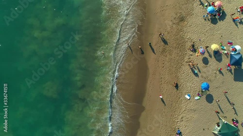 4k aerial birds eye video view of a beautiful sunny beach with people
