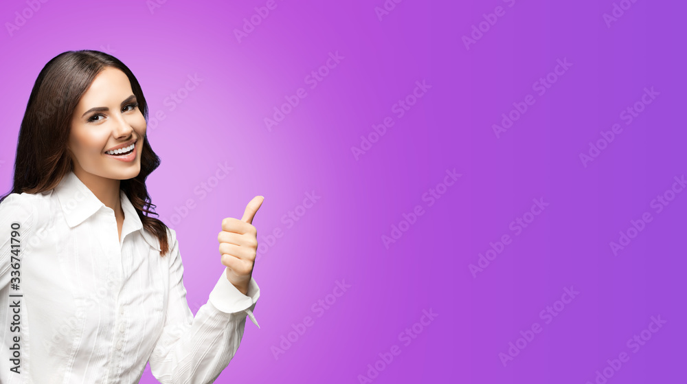 Portrait of happy smiling young excited businesswoman, showing thumb up hand sign gesture. Success in business concept studio shot. Over purple violet color background. Portrait of happy smiling young excited businesswoman, showing thumb up hand sign gesture. Success in business concept studio shot. Over purple violet color background.