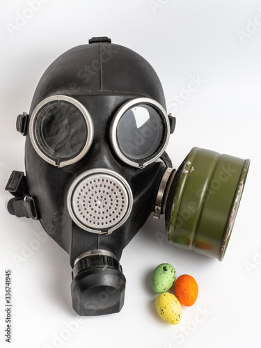 The celebration of Easter during the epidemic of the coronavirus. Easter eggs and a gas mask on white background. © MIKHAIL