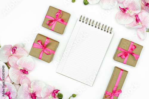 flat lay of Gift present boxes with pink ribbon and orchid flowers. Note book or diary writing. spring concept