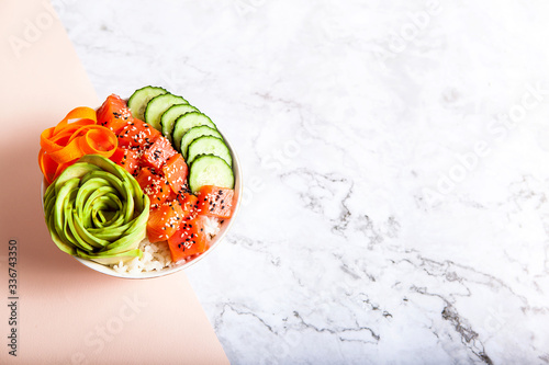 Salmon poke with avocado, cucumber, and rice on marble background , top view. Asian trendy food