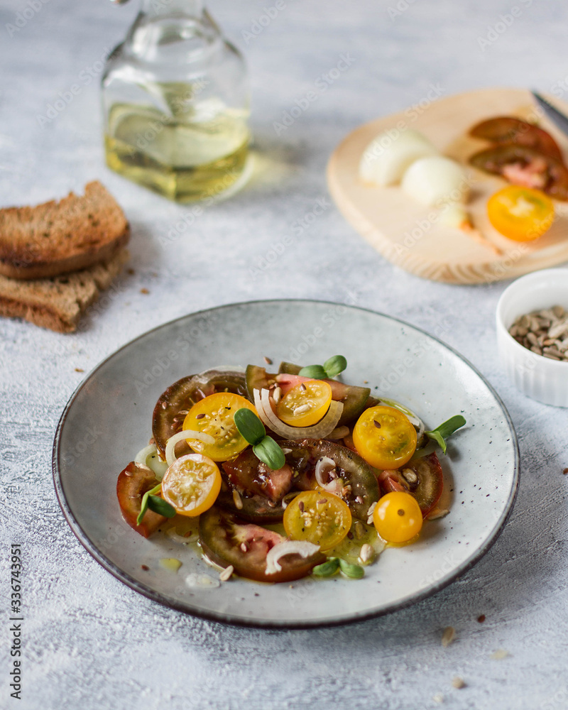 Salad of yellow and black tomatoes on a gray plate with greens.