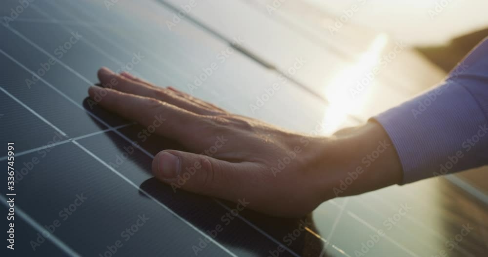 Close up of an young engineer hand is checking an operation of sun and cleanliness of photovoltaic solar panels on a sunset. Concept:renewable energy, technology,electricity,service, green,future