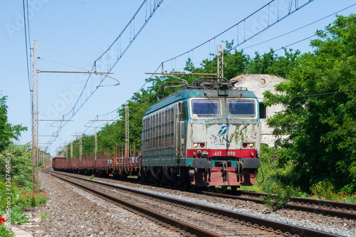 Un treno merci con carico di barre di acciaio in transito nei pressi di Latina, Italia