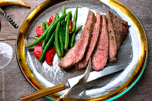 Grilled flank steak slices with beans and cherry tomatoes on plate