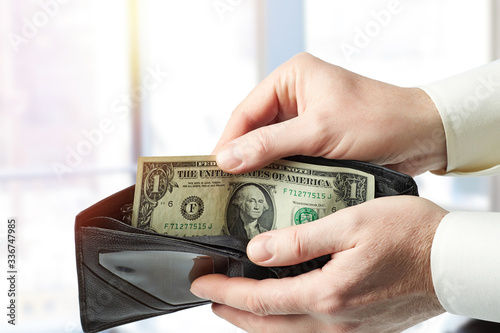 A close-up of a mature man's hand pulls out a 1 US dollar