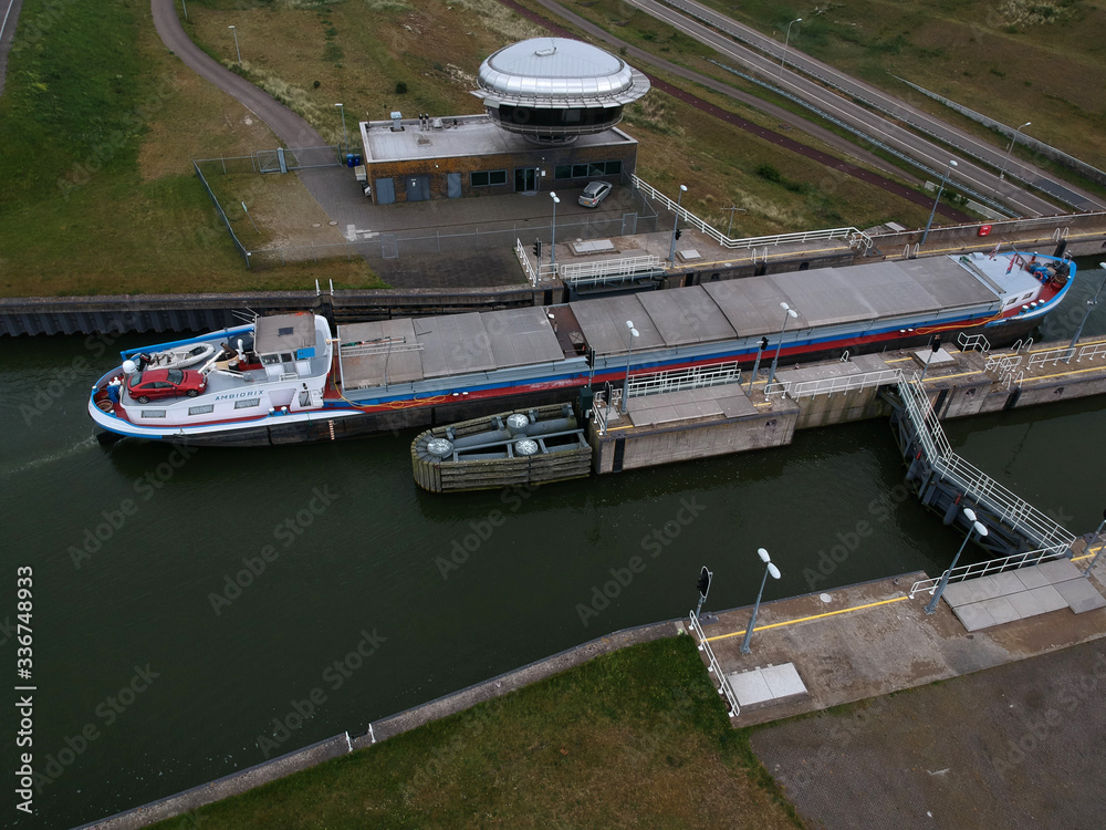 Photograph made with a drone of an Inland navigation vessel in the lock of near enkhuizen, this lock is a naviduct where the traffic passes under the concrete lock