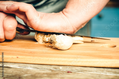 male hands crush garlic on a kitchen board