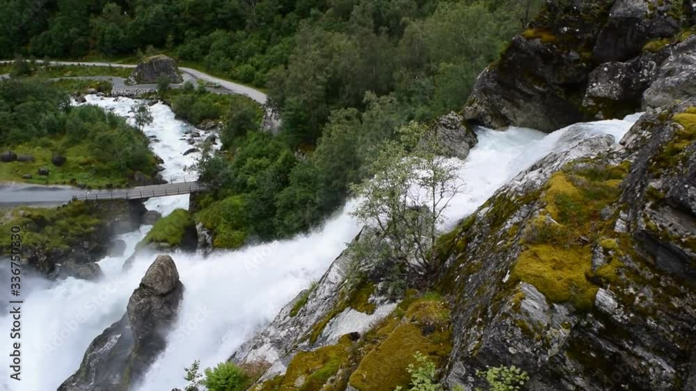 Waterfall and river which is located near path to the Briksdalsbreen (Briksdal) glacier. The melting of this glacier forms waterfall and river with clear water. Jostedalsbreen National Park. Norway. Waterfall and river which is located near path to the Briksdalsbreen (Briksdal) glacier. The melting of this glacier forms waterfall and river with clear water. Jostedalsbreen National Park. Norway.