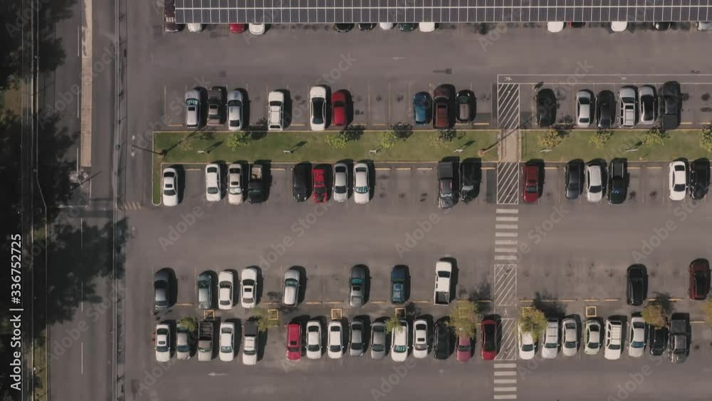 Aerial bird's eye view of rows of cars in a parking lot with a solar panel