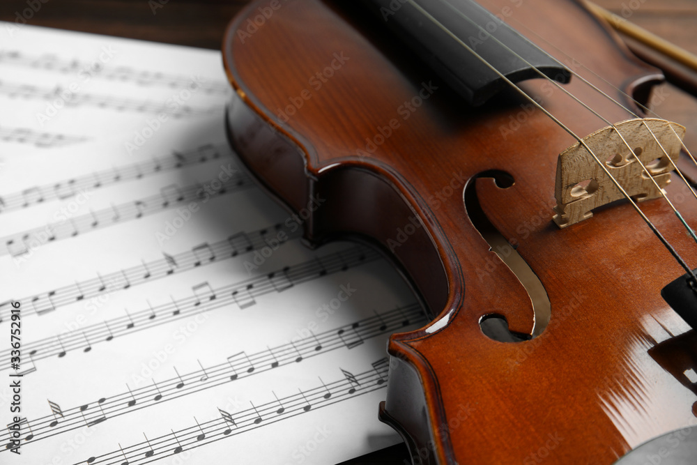 Fototapeta premium Beautiful violin and note sheets on table, closeup