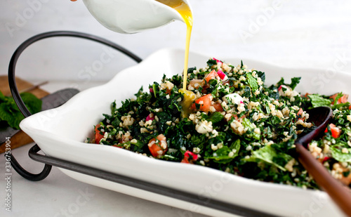 Dressing being poured on kale tabbouleh photo