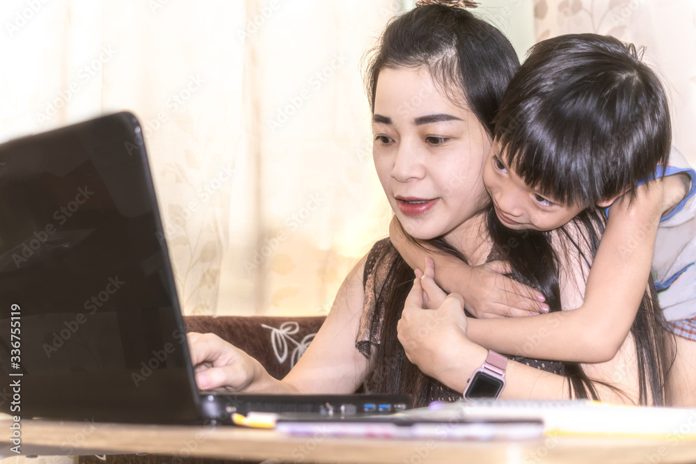 Happy young woman working and learning online from laptop. Mother and kid smile work from home concept. Happy young woman working and learning online from laptop. Mother and kid smile work from home concept.