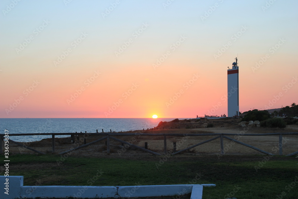 Atardecer en la playa de Matalascañas con Faro. Huelva.