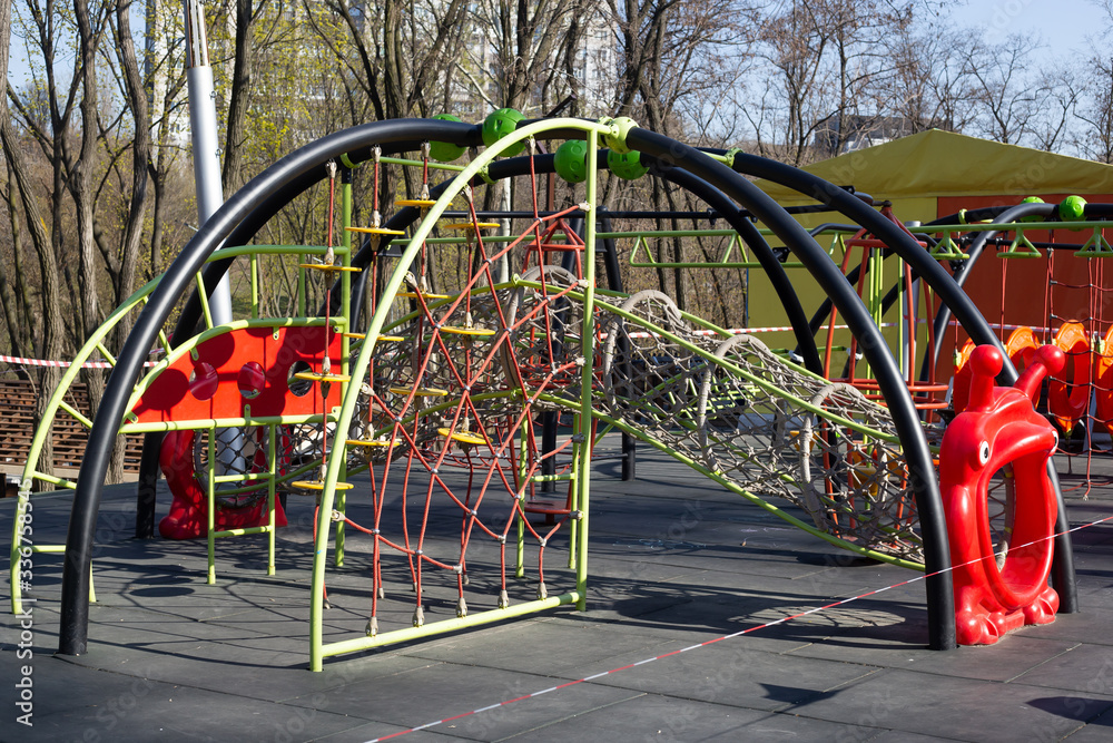 Red caution tape on kids playground, closed due to COVID-19 quarantine Red caution tape on kids playground, closed due to COVID-19 quarantine