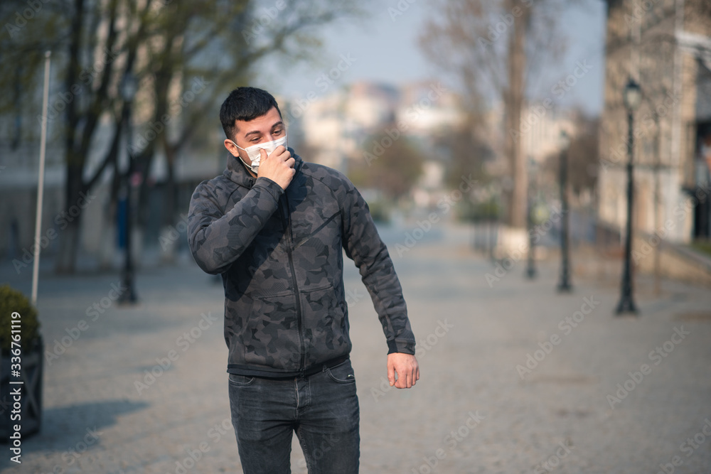 Virus covid-19. A man in a medical mask sneezes and coughs on a street in a city in Europe. Pandemic mask virus protection. Virus covid-19. A man in a medical mask sneezes and coughs on a street in a city in Europe. Pandemic mask virus protection.