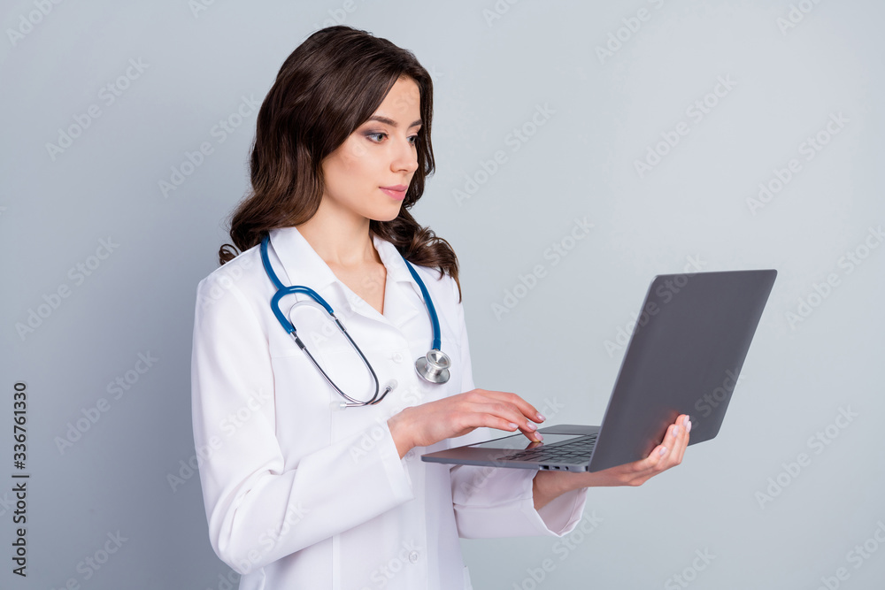 Photo of focused experienced doc girl have corona virus patient pneumonia disease use laptop online best world doc communication workshop wear white uniform isolated gray color background Photo of focused experienced doc girl have corona virus patient pneumonia disease use laptop online best world doc communication workshop wear white uniform isolated gray color background