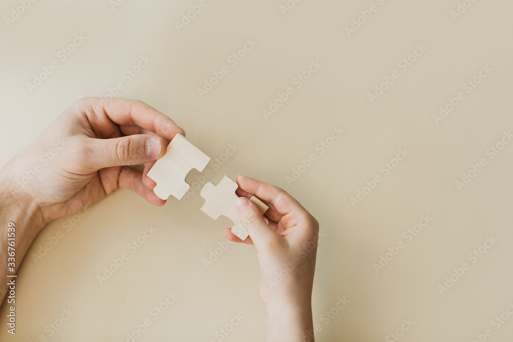 wooden puzzles are combined in the hands of a child and an adult, home games with the family wooden puzzles are combined in the hands of a child and an adult, home games with the family
