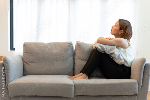 Depression and sadness concept,Young asian woman covering her face sitting on sofa in home.