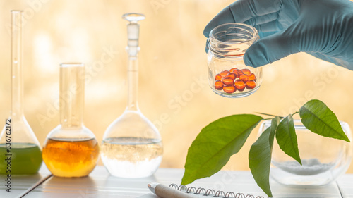 Hand of a pharmacist holds a jar with vitamins in the laboratory photo