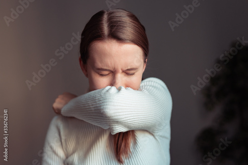 Cough in tissue covering nose and mouth when coughing. European woman sick with flu at home.