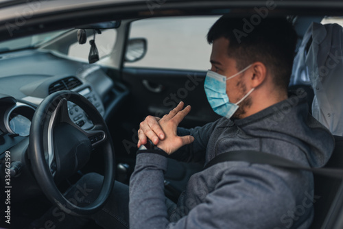 A man sits car and washes his hands with antiseptic gel. healthcare concept in car. The mask is white on the face. coronavirus, disease, infection, quarantine, covid-19 © Evghenii Blanaru
