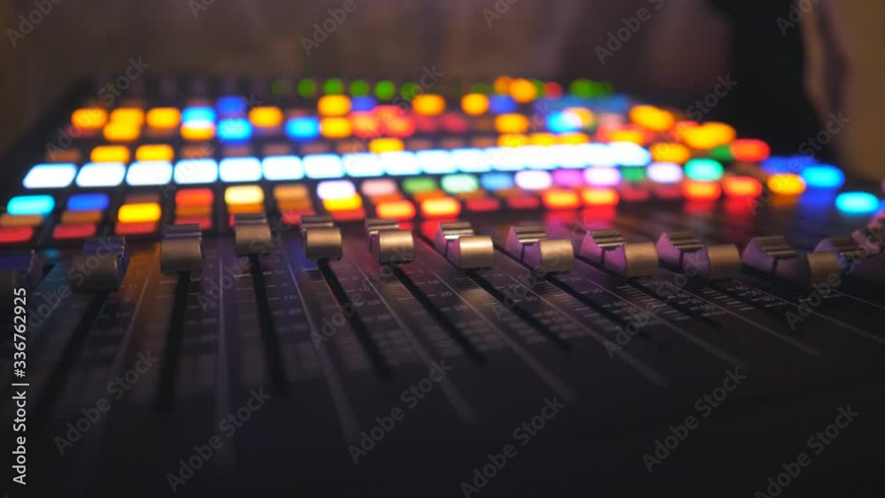 Close up of dj remote with moving buttons. Working process on recording studio. Amplifier and balance of sound. Musical player at night party in club. Bright glow at background. Dolly shot Slow motion