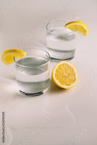 Lemon water in a glass with a slice of lemon on a light background with a place for text side view