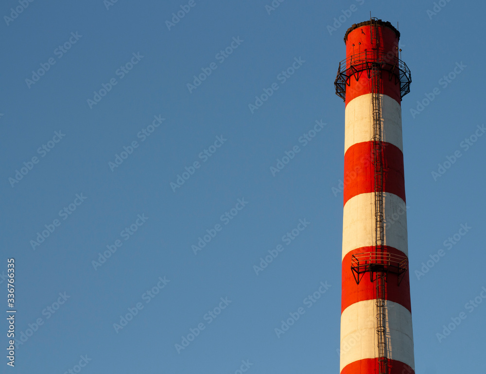 large red white factory chimney against a blue sky.copyspace for text. large red white factory chimney against a blue sky.copyspace for text.
