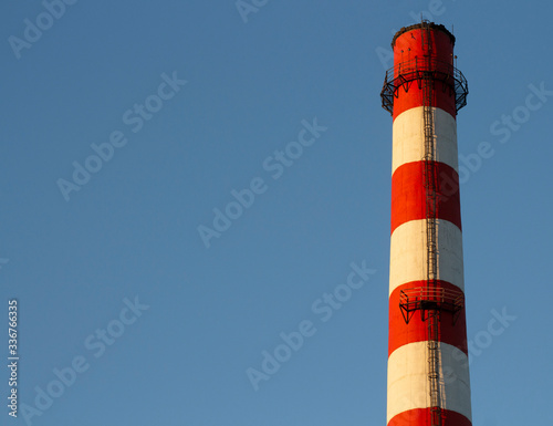 large red white factory chimney against a blue sky.copyspace for text.