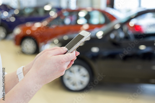 Woman dealer using mobile smart phone at dealer showroom. Modern working process.