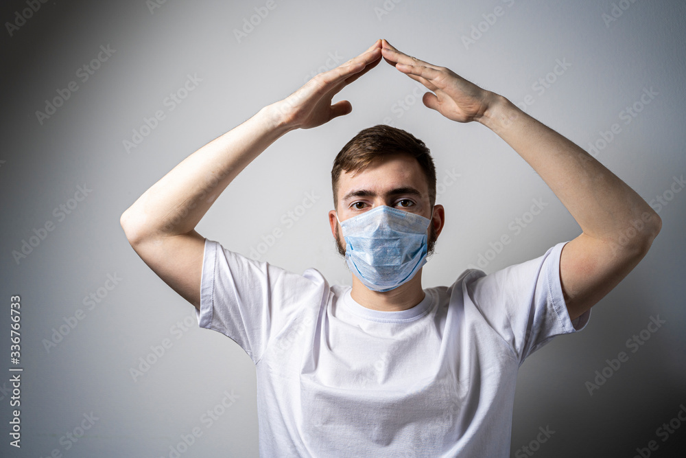 A man in a medical mask shows with his hands the gesture I'm in the house. Stay at home. Self-isolation A man in a medical mask shows with his hands the gesture I'm in the house. Stay at home. Self-isolation