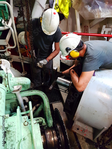 Expert mechanic technicians working onboard a ship engine room