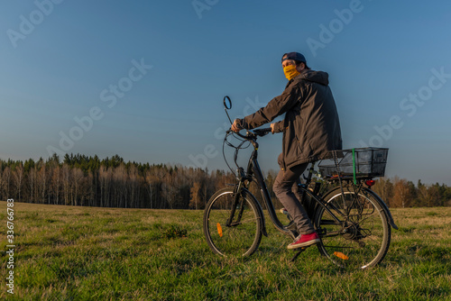 Fototapeta Naklejka Na Ścianę i Meble -  Young man on black electric bike in spring color evening