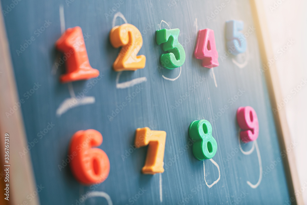 Learning numbers on a blackboard with colorful magnets and handwriting on blackboard during homeschooling at quarantine