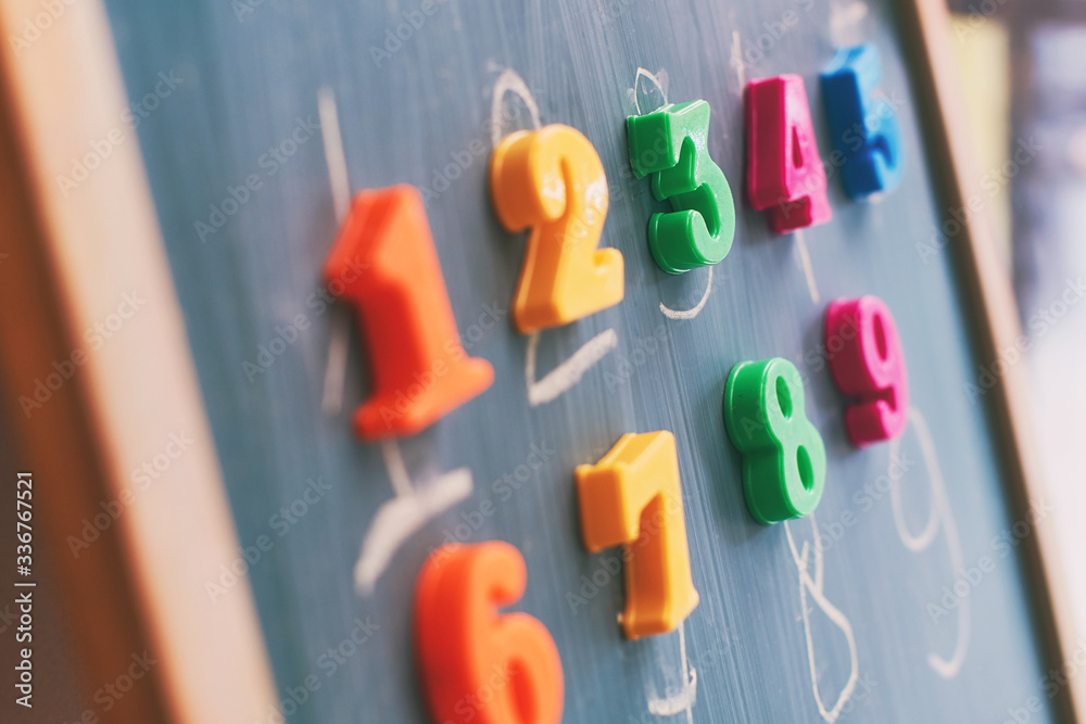Learning numbers on a blackboard with colorful magnets and handwriting on blackboard during homeschooling at quarantine