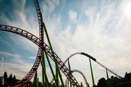 Roller coaster silhouette at sunset in an amusement park. Summer panorama. Copy space.
