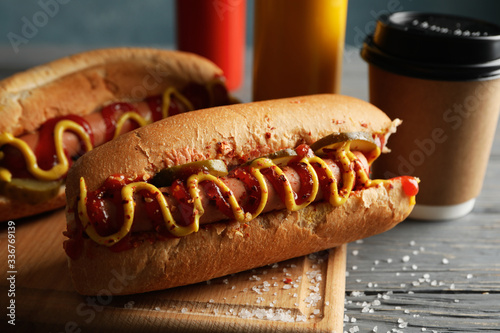 Fototapeta Naklejka Na Ścianę i Meble -  Tasty hot dogs, coffee and sauces on wooden background