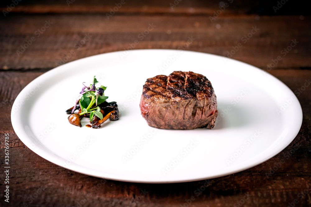 Grilled beef tenderloin Steak on a white platter with vegetables served in a restaurant. Grilled beef tenderloin Steak on a white platter with vegetables served in a restaurant.